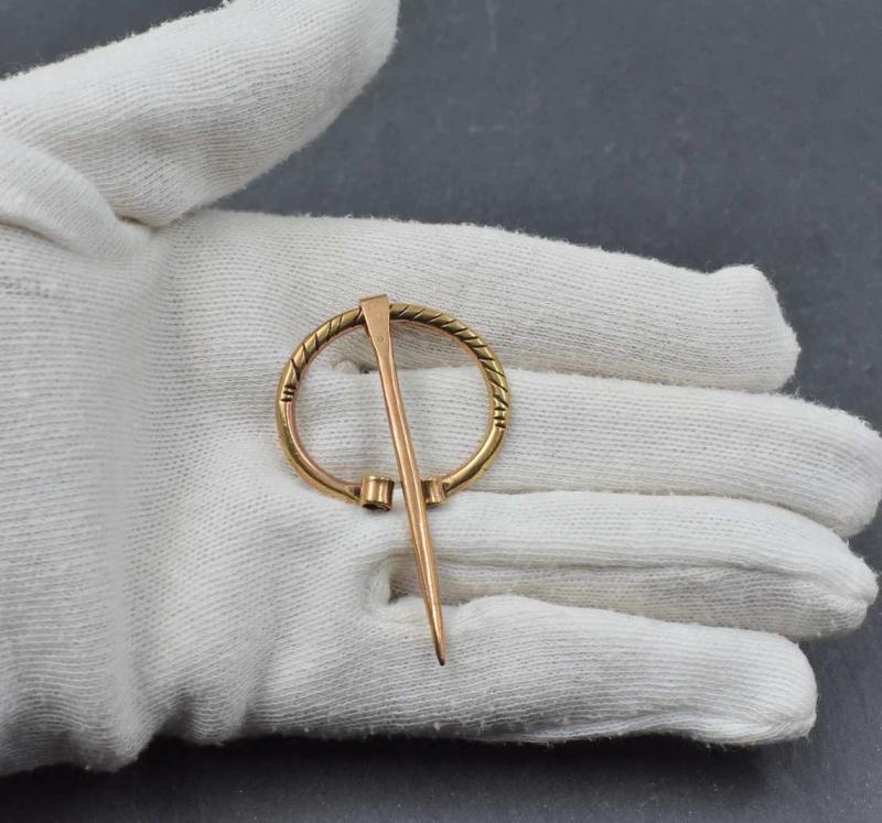 Kleine Wikinger Ringfibel mit eingerollten Enden aus Bronze auf der Hand